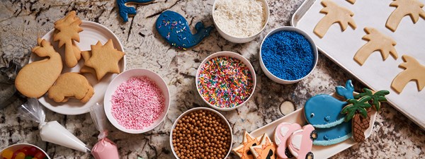 Cookie making ingredients laid out including sprinkles, sweets and piping icing