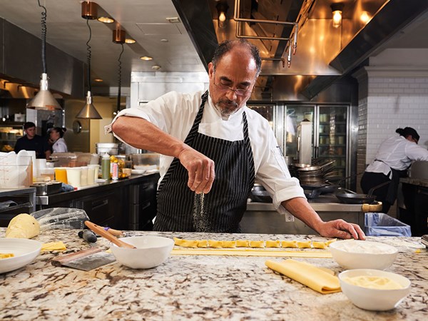 Chef sprinkling flour on fresh homemade pasta in kitchen