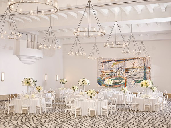 White chairs and round tables set up for a wedding reception in the ballroom