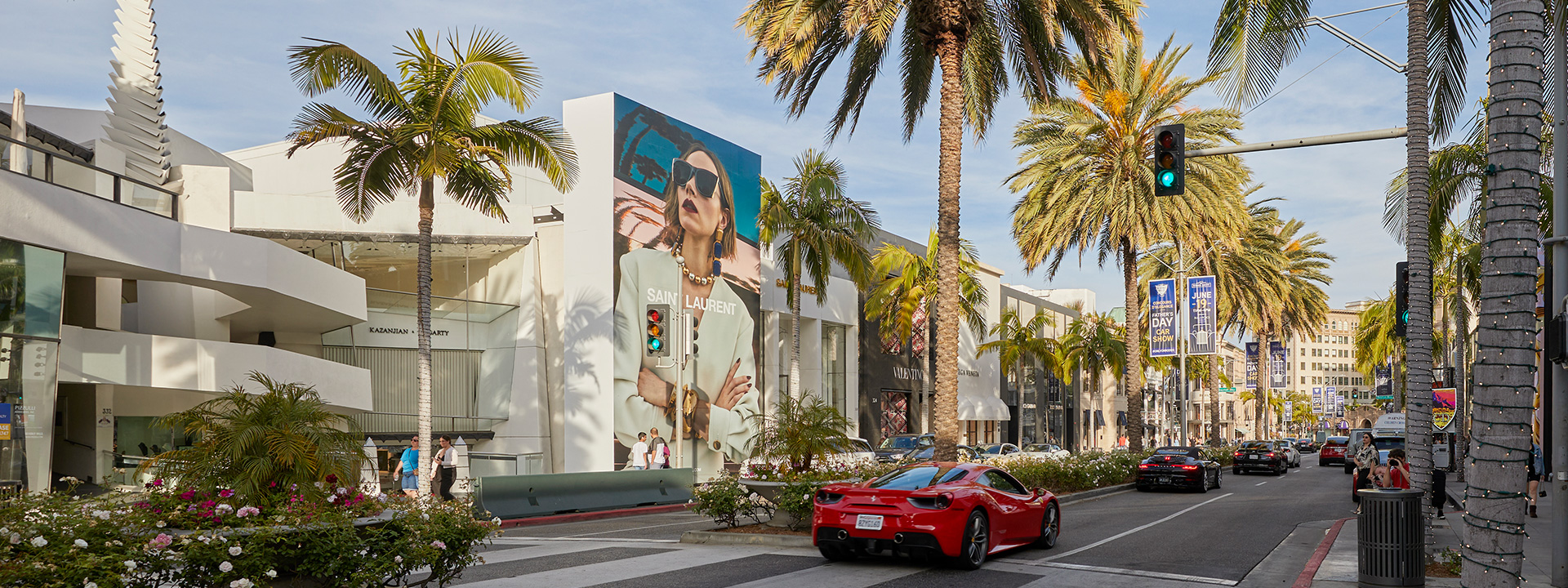 Red sports car driving down Rodeo Drive with palm trees and designer shops