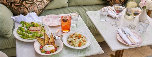 Spread of different small plates with toasted bread, burrata, salad and cocktails placed upon tables at Dante