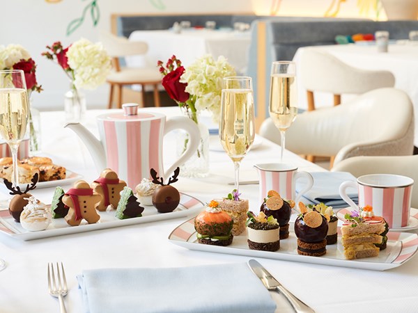 Festive holiday afternoon tea sandwiches and desserts with pink and white china and champagne flutes