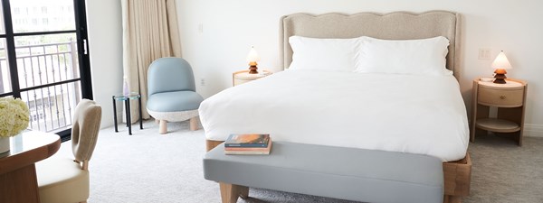 King bed with white bedding and curved headboard in bedroom of suite