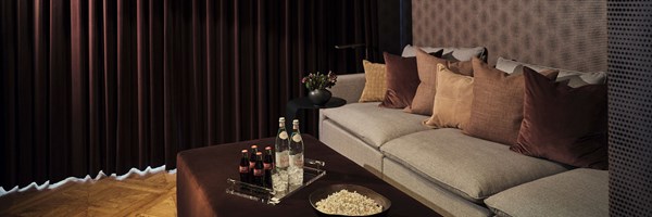 Grey sofa in a blackout room with a velvet curtain, with popcorn and treats on a coffee table