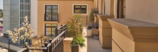 Large terrace of the Three-bedroom Residence with a table and chairs under the sunlight